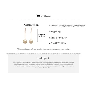 Detailed view of silver needle drop earrings with sparkling rhinestones and pearls