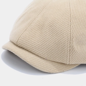 Detail of light khaki newsboy cap showing twill fabric texture and stitching on the brim