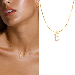 Detail of a gold-plated letter E enamel pendant necklace shown on a model and a white backdrop