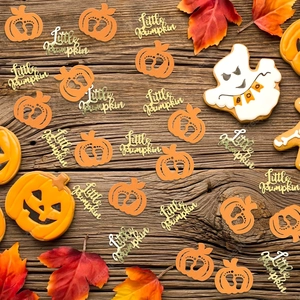 Glittery Little Pumpkin confetti and orange pumpkins scattered on a rustic wooden table