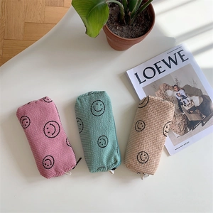 Close-up of corduroy makeup bags with smiley face patterns in pink, green, and beige colors