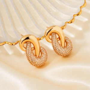 Elegant French vintage gold knot earrings with zircon pavé on champagne silk background