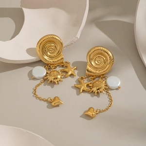 Detailed shot of gold sun and starfish tassel earrings with pearl on stone pedestal