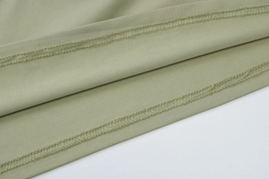 Close-up of olive green knit fabric showing premium double-needle stitching and texture
