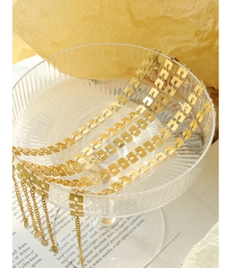 Dettaglio macro del bracciale geometrico dorato su vassoio in vetro placcato oro 18 carati