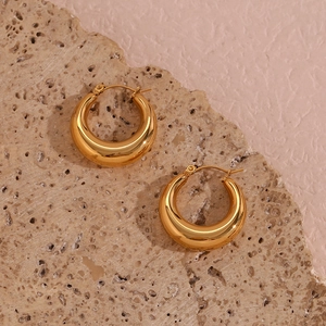 Detailed macro view of 25mm 18K gold plated thick hoop earrings on textured stone