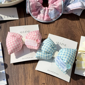 Detail of blue and pink plaid bow hair clips with buttons on a rustic wood surface