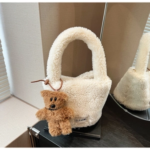 Détail du sac seau en peluche crème avec texture polaire douce et charm ours marron