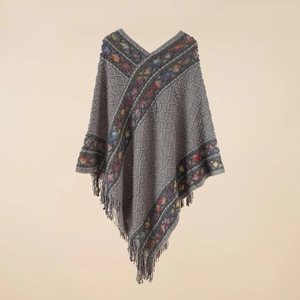 Close-up of gray knit poncho featuring V-neck, fringe tassels and colorful patterns