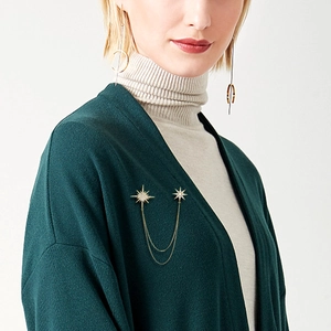 Detail of gold starburst brooch with double chains worn on a model's outfit