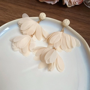 Detailed macro view of cream chiffon flower petals and gold tassel drop earrings