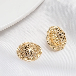 Detail of golden hollow mesh dome pendants for jewelry making on white satin