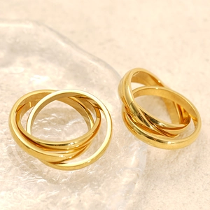 Detail of three-band interlocking 18k gold plated stainless steel ring on glass tray