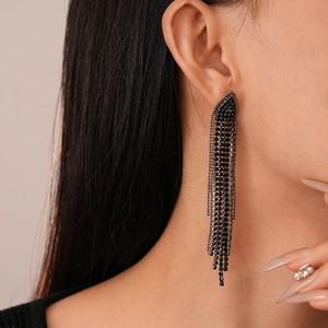 Close-up of black fringe earrings featuring long multi-row chains and crystal details