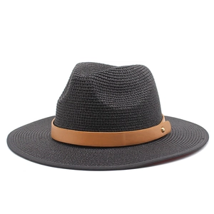 Detail of black straw fedora hat featuring a camel leather band and gold rivet accent