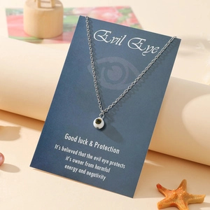 Close-up of a silver stainless steel evil eye pendant necklace on a blue display card