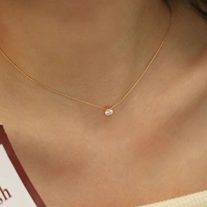 Close-up of minimalist gold chain necklace with a single round sparkling zircon pendant