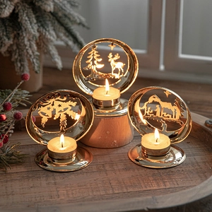 Three-piece gold metal Christmas candle holders with festive cutout patterns on wood tray