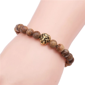 Close-up of brown agate beaded bracelet with a golden lion head charm on model wrist