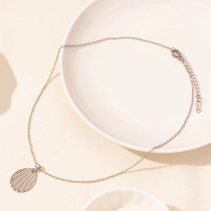 Detail of silver stainless steel necklace with textured ripple oval pendant on white plate