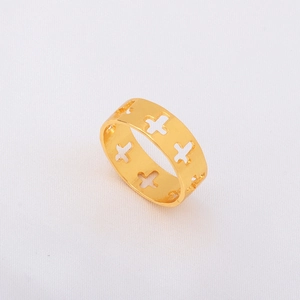 Macro shot of gold-plated openwork cross ring on a textured white fabric background