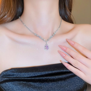 Close-up of pink teardrop crystal pendant necklace worn on neck with silver chain