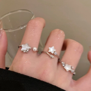 Close-up of adjustable star ring with white pearl and shell inlay on woman's finger