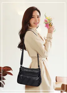 Detail of black soft leather crossbody bag with multi-zipper layers and stitched pattern