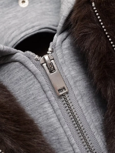 Detail eines silbernen Metallreißverschlusses und braunem Pelzkragen an einer grauen Jacke