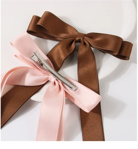 Detail of pink and brown ribbon bow hair clips with textured fabric and metal duckbill grip