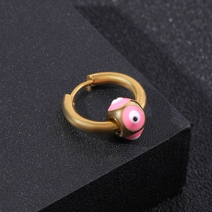 Macro shot of gold hoop earring featuring pink and white evil eye beads on black base