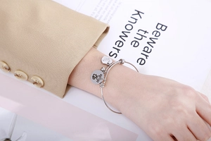 Detailed view of silver heart and girl charms on adjustable stainless steel bracelet