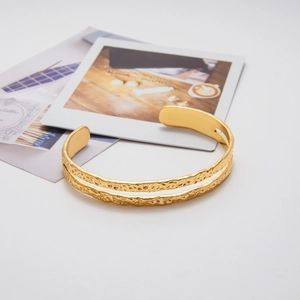 Detail view of 18k gold double-layered cuff bracelet with textured hammered finish
