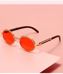 Close-up of vintage rhinestone frame sunglasses with red lenses and UV400 gold metal temples