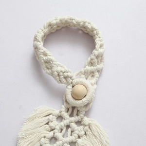 Macro detail of handmade cotton rope curtain tieback with wooden bead and bohemian tassels