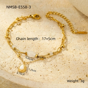 Détail du bracelet doré double couche avec pierre oeil de chat et pendentif goutte