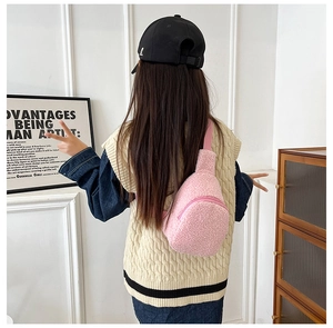 Pink plush kids crossbody bag styled with a beige vest in a modern indoor setting