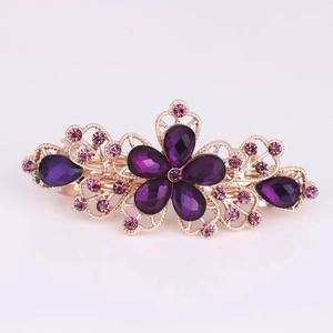 Close-up of small rose gold flower hair clip with deep purple teardrop rhinestones
