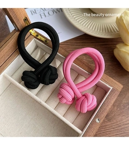 Détail d'élastiques à cheveux noirs et roses à double brin avec nœuds dans une boîte en bois