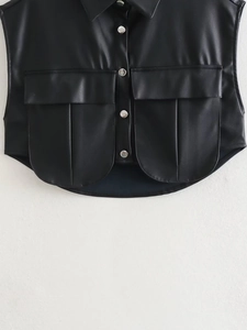 Detail of black faux leather vest featuring silver metal buttons and two large cargo pockets