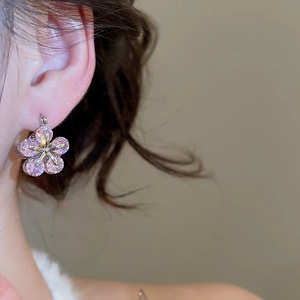 Close-up of pink zircon flower earrings on ear showing delicate sparkle and silver finish