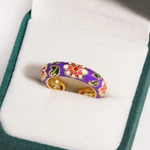 Macro shot of purple enamel flower ring with gold plating in a white velvet jewelry box