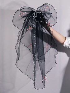 Detail of black tiered tulle bridal veil with white pearl chains and pink bow accent