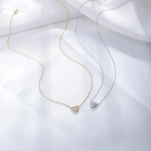 Detail of silver and gold heart necklaces with zircon stones on soft white fabric