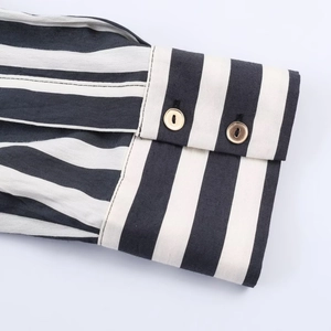 Detailed macro view of black and white striped shirt cuffs with gold round buttons