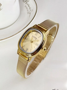 Elegant gold mesh strap watch with rectangular dial styled on a lifestyle magazine