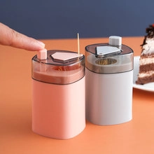 Manual press operation of automatic pink dental floss pick dispenser on tabletop