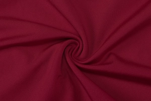 Macro shot of burgundy ribbed knit fabric showing fine vertical texture and soft drape