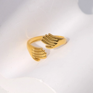 Macro shot of hug hands open ring in warm gold finish showing detailed palm textures