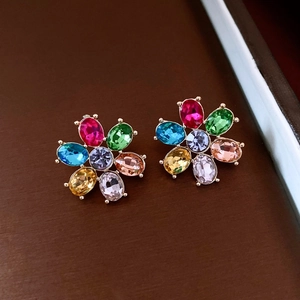 Close-up of vintage flower earrings with colorful crystals on a dark wood background